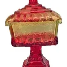 Vintage Amberina glass pedestal candy dish with matching lid, featuring pressed geometric patterns.