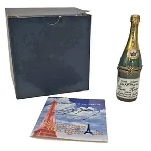 Limoges France porcelain champagne bottle trinket box with hinged brass closure, original box, and certificate of authenticity.