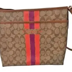 Coach Signature canvas crossbody bag featuring brown monogram print with a central pink and purple stripe accent and brown leather trim.
