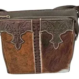 Western-style leather and hair-on-hide shoulder bag featuring floral embossed trim, white contrast stitching, and central laced detailing.
