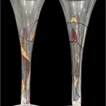 Pair of modern tall clear glass champagne flutes featuring abstract hand-painted stained glass style motifs with metallic gold accents.