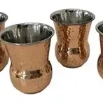 Set of four hammered copper tumblers with stainless steel linings, featuring a flared rim and bulbous base.