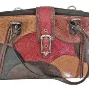 Western-style patchwork embossed leather handbag featuring multi-colored tooled panels, a center buckle closure, and shoulder straps.