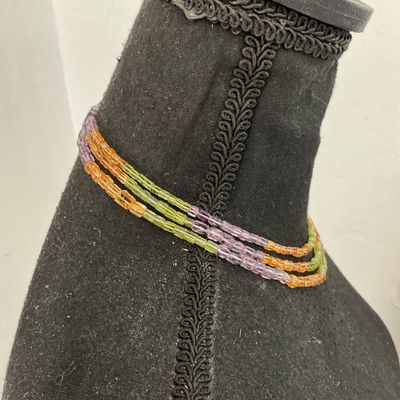 Sale Photo Thumbnail #263: A multi-strand beaded choker necklace featuring small, square cylinder beads in alternating sections of purple, light green, and amber orange. Finished with a gold-tone barrel clasp. In good pre-owned condition with no missing beads visible.