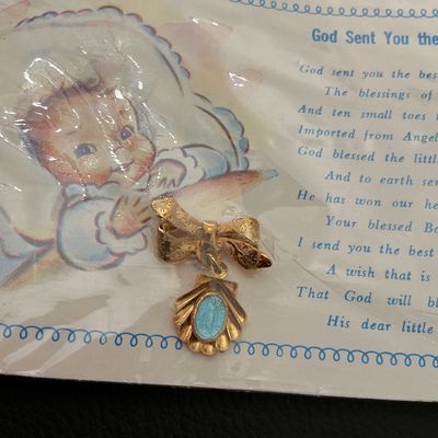 Sale Photo Thumbnail #267: Vintage gold-tone bow pin featuring a shell-shaped dangle charm with a blue enamel center oval. Comes mounted on its original illustrative printed card titled 'God Sent You the Best He Had' inside plastic packaging. Card shows light storage wear and minor