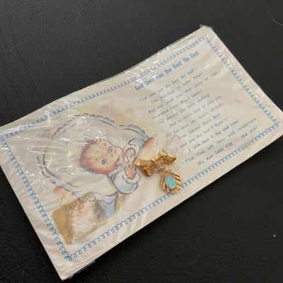 Sale Photo Thumbnail #269: Vintage gold-tone bow pin featuring a shell-shaped dangle charm with a blue enamel center oval. Comes mounted on its original illustrative printed card titled 'God Sent You the Best He Had' inside plastic packaging. Card shows light storage wear and minor