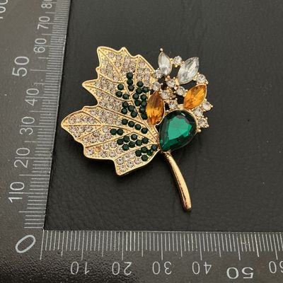 Sale Photo Thumbnail #211: Gold-tone leaf brooch featuring pave set clear, dark green, amber, and light green rhinestones, with larger marquise and teardrop faceted glass stones. Measures approximately 55mm x 50mm. Good condition with all stones intact and bright finish.
