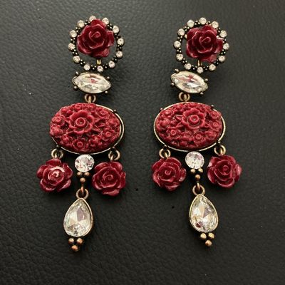 Sale Photo Thumbnail #183: A pair of elaborate statement dangle earrings featuring carved red resin floral rose motifs set in antiqued brass-tone metal. Detailed with faceted clear rhinestones and teardrop crystal drops. Each earring measures approximately 3.25 inches (82 mm) in le