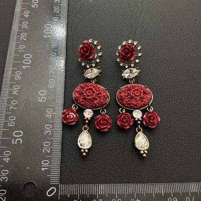 Sale Photo Thumbnail #185: A pair of elaborate statement dangle earrings featuring carved red resin floral rose motifs set in antiqued brass-tone metal. Detailed with faceted clear rhinestones and teardrop crystal drops. Each earring measures approximately 3.25 inches (82 mm) in le