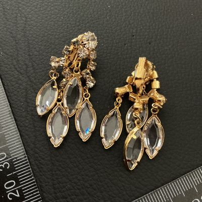 Sale Photo Thumbnail #245: Pair of vintage gold-tone clip-on dangle earrings set with clear round rhinestones and navette/marquise-cut glass stones in dangling drops. Each earring measures approximately 2 inches (50 mm) in length. Shows minor vintage surface wear; all stones are in