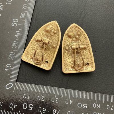 Sale Photo Thumbnail #207: Pair of vintage gold-tone clip-on earrings in a crest or shield design featuring crossed swords, colorful cabochons (green and fuchsia/pink), and clear plus red rhinestones. Each earring measures approximately 45 mm x 30 mm (1.75 in x 1.2 in). Show minor 
