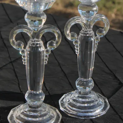 Sale Photo Thumbnail #13: Pair of vintage clear pressed glass candlesticks with decorative curved side handles and stepped octagonal bases.