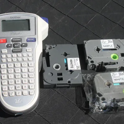 Sale Photo Thumbnail #43: Brother P-touch handheld electronic label maker with three TZe laminated tape cartridges, including one sealed in plastic.