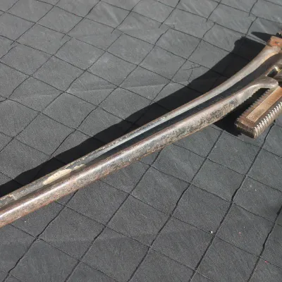 Sale Photo Thumbnail #7: Vintage heavy-duty cast iron pipe wrench with an adjustable knurled nut, showing age-related patina and surface rust.