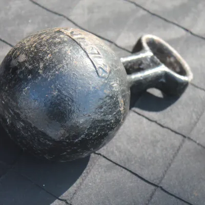 Sale Photo Thumbnail #37: Vintage heavy black cast iron round weight with attached attachment loop, showing minor surface wear and patina.