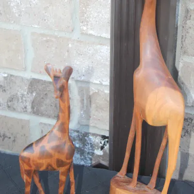 Sale Photo Thumbnail #33: Pair of hand-carved wooden giraffe statues, featuring one with detailed geometric spot carvings and one smooth-finished stylized figure.