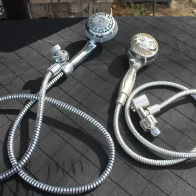 Sale Photo Thumbnail #66: Pair of handheld shower heads with flexible metal hoses, including one chrome and one brushed finish unit.