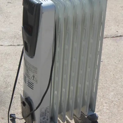 Sale Photo Thumbnail #40: DeLonghi portable oil-filled radiator heater on casters, showing light scuffing from general use.