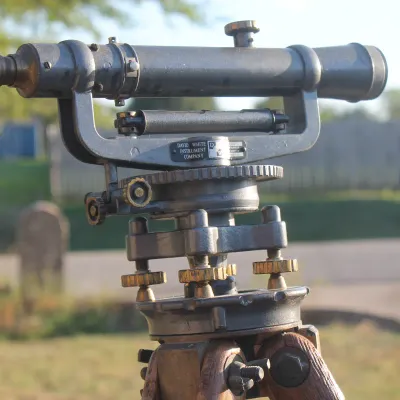 Sale Photo Thumbnail #16: Vintage David White Instrument Company surveyor transit level mounted on a wooden tripod, featuring brass adjustment knobs and aged patina.