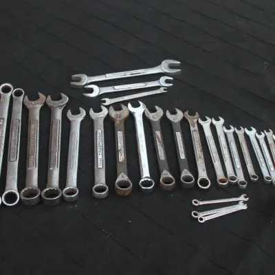 Sale Photo Thumbnail #56: Large assortment of vintage Craftsman combination, open-end, and specialty wrenches arranged on a dark surface.