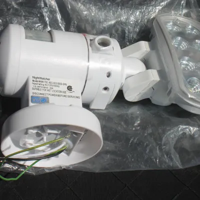 Sale Photo Thumbnail #46: NightWatcher model NW 700 outdoor LED security light with built-in motion sensor, featured in white plastic housing with exposed wiring.