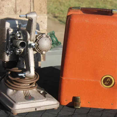 Sale Photo Thumbnail #15: Vintage Revere Model 85 8mm movie projector in a hammered metallic finish, complete with its original textured orange carrying case.