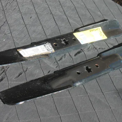 Sale Photo Thumbnail #48: Pair of black lawn mower replacement blades, including a Cub Cadet branded blade with star-shaped center mounting holes.