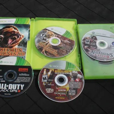 Sale Photo Thumbnail #65: Collection of four Xbox 360 video game discs including Call of Duty: Black Ops III, Borderlands, Assassin's Creed II, and Cabela's Dangerous Hunts 2013 with open cases.