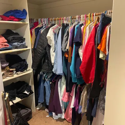 Sale Photo Thumbnail #83: Walk-in closet filled with assorted modern clothing on hangers and folded on built-in shelving.