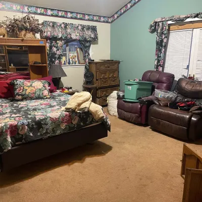 Sale Photo Thumbnail #80: Bedroom suite featuring a king-size bed with an oak headboard pier unit, matching floral bedding and window treatments, a wooden tall chest, and two leather recliners.