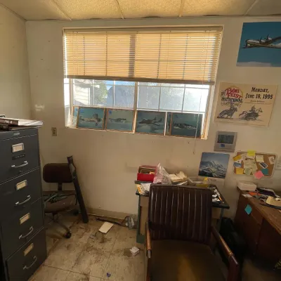 Sale Photo Thumbnail #55: Home office filled with vintage furniture, including a metal filing cabinet, brown leather armchairs, and aviation-themed wall art.