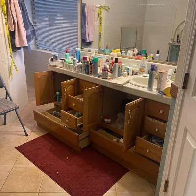 Sale Photo Thumbnail #81: Large wooden bathroom vanity with open drawers and cabinets, filled with assorted personal care products, toiletries, and cosmetics.