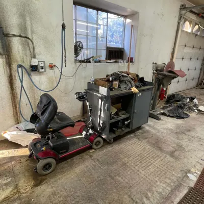 Sale Photo Thumbnail #58: Red Go-Go electric mobility scooter parked in a workshop next to a metal rolling utility cart and a pedestal disc sander.