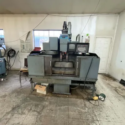 Sale Photo Thumbnail #25: Large industrial CNC vertical milling machine featuring an enclosed workspace and an integrated control panel with display screen.