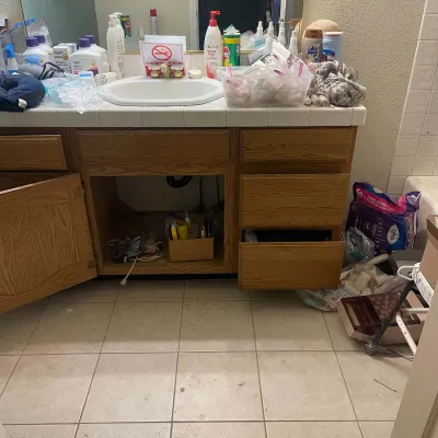 Sale Photo Thumbnail #85: Wooden bathroom vanity with tiled countertop, surrounded by various toiletries, personal care supplies, and medical equipment.