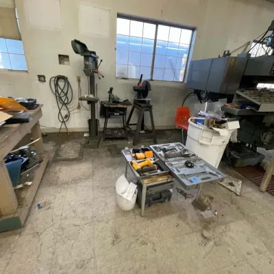 Sale Photo Thumbnail #24: Workshop loaded with various industrial machinery and power tools, including a drill press, cut-off saw, and power tool cases.