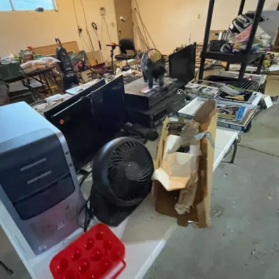 Sale Photo Thumbnail #74: Assorted household items and electronics displayed on a folding table, including a desktop computer tower, small desk fan, and audio-video equipment.