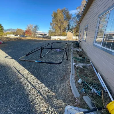Sale Photo Thumbnail #21: Black metal truck bed ladder rack resting on a gravel driveway alongside various yard tools and equipment.