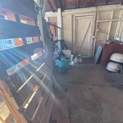 Sale Photo Thumbnail #37: Garage workshop filled with assorted items including wooden pallets, buckets, Dish Network satellite domes, and various home maintenance supplies.