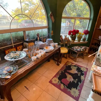 Sale Photo Thumbnail #98: Collection of kitchenware, glassware, and home decor displayed on a long wooden console table and surrounding area, alongside a rooster-patterned area rug.