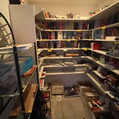 Sale Photo Thumbnail #42: Walk-in closet lined with white built-in shelving packed with various VHS tapes, DVDs, books, and storage boxes.