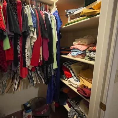 Sale Photo Thumbnail #90: Walk-in closet filled with assorted hanging clothing and stacked linens on built-in shelving.