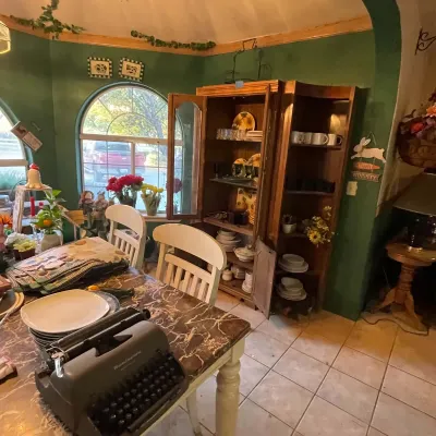 Sale Photo Thumbnail #97: Vintage Remington manual typewriter on a faux-marble dining table, set in a dining room featuring a large wooden hutch filled with dishware.