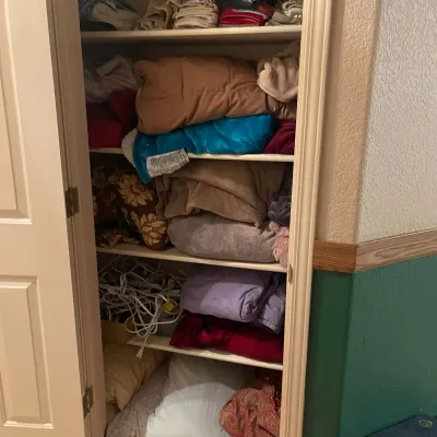 Sale Photo Thumbnail #92: Linen closet packed with various folded blankets, pillows, sheets, and assorted electrical extension cords on lower shelves.