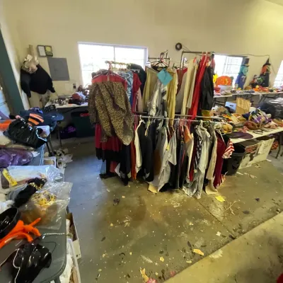 Sale Photo Thumbnail #17: Clothing racks filled with various costumes, garments, and accessories set up in a workshop or garage area.