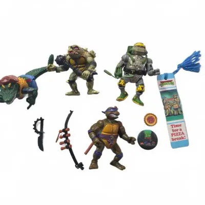 Sale Photo Thumbnail #27: Collection of vintage Playmates Teenage Mutant Ninja Turtles action figures and accessories from the late 1980s to early 1990s, including Leatherhead, Tokka, Astronaut Michelangelo, and Donatello alongside weapon accessories, a TMNT bookmark, and pinback 