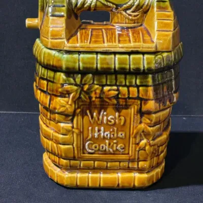 Sale Photo Thumbnail #43: Vintage ceramic wishing well cookie jar featuring a yellow and green drip glaze and embossed 'Wish I Had a Cookie' lettering on the front.