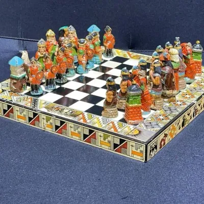 Sale Photo Thumbnail #42: Hand-painted Peruvian chess set featuring Inca vs. Spanish Conquistador figures, displayed on a matching decorated board.