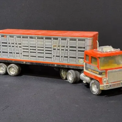 Sale Photo Thumbnail #94: Vintage Nylint Farm Transport semi-truck and livestock trailer in orange and silver pressed steel, showing light wear.