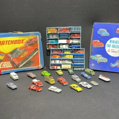 Sale Photo Thumbnail #80: Vintage Matchbox carrying cases and trays alongside an assortment of die-cast toy cars, trucks, and vehicles showing moderate wear.